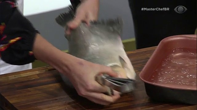 Helena Rizzo dá aula de como filetar peixe para os participantes Reprodução TV